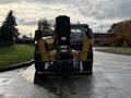 A 2014 Caterpillar TL1055C telehandler facing forward with a large front fork attachment and yellow and black coloring