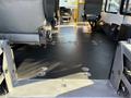 Interior view of a 2016 Ford Econoline showing a clean floor with metal tie-down points and several seats partially installed