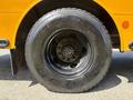 Close-up of a large black tire with a multi-bolt pattern on a yellow vehicle showing the tread and sidewall details