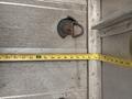 A measuring tape laid out next to a rusted latch on a metal surface, likely part of a 2012 Ford E-450 vehicle