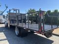 A 2011 International 4300 truck with a flatbed designed for carrying heavy loads featuring railings on the sides and a rear hitch for towing