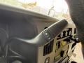 Close-up of the gearshift lever in a 2020 Chevrolet Express with a plus and minus button for gear selection and dashboard controls visible behind it