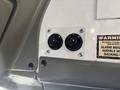 Two circular control knobs mounted on a white panel with a warning label nearby