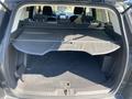 The interior of a 2016 Ford Escape with a spacious cargo area featuring a retractable cover and dark carpeting