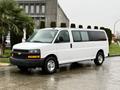 A white 2021 Chevrolet Express van parked with side windows and a black grille featuring the Chevrolet logo