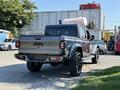 A 2021 Jeep Gladiator with a gray exterior and black wheels parked in an area with other vehicles visible in the background