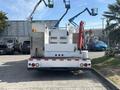 A 2006 International 4300 truck with a flatbed and mounted equipment at the rear including work arms and tools