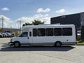 A white 2017 Chevrolet Express bus with large windows and a raised roof parked on a concrete surface