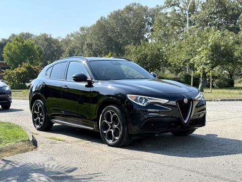 A black 2020 Alfa Romeo Stelvio with a distinctive grille and stylish alloy wheels parked in a driveway