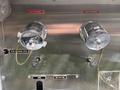 Two metal valves labeled No 4 Discharge and No 2 Discharge with discharge pipes and a rear discharge drain located below them on a Freightliner FL80 vehicle