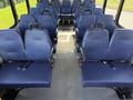 Interior of a 2020 Chevrolet Express featuring rows of blue fabric seats with seat belts and a spacious layout