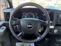 A 2013 Chevrolet Express with a black steering wheel featuring a Chevy logo and dashboard gauges visible behind the wheel
