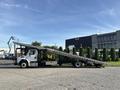 A 2022 Freightliner M2 106 truck with a flatbed and ramp extended for loading or unloading vehicles