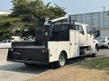 A 2006 Sterling Acterra truck with a flatbed and utility box is parked, featuring a mounted crane and black mesh storage compartments on the rear