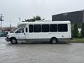 A 2018 Chevrolet Express van in white with a large side window and a raised roof parked at an angle on a wet surface