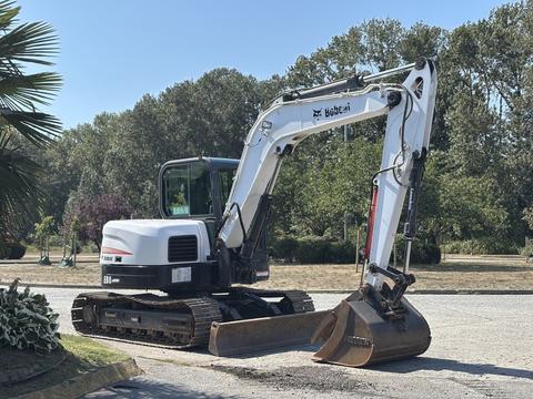 A 2010 Bobcat E80 excavator with a white and black design features a large digging bucket attached to a long arm and tracks for mobility.