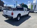 A white 2016 Ford F-350 SD truck with a flatbed and a black ladder rack visible at the rear