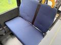 A blue upholstered bus seat with a safety belt attached to the side
