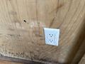 A white electrical outlet mounted on a wooden wall inside a trailer