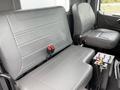 Two gray vinyl seats in a vehicle cabin with safety seatbelts and controls beside them