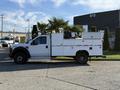 A 2009 Ford F-550 truck with white service body and mounted equipment on the bed, featuring a yellow light on top and black wheels