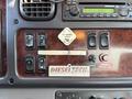 Dashboard of a 2011 Freightliner M2 106 displaying various controls including windows, parking brake, and a radio with a wood grain finish