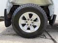 Close-up of a silver alloy wheel with five spokes mounted on a large off-road tire featuring an aggressive tread pattern