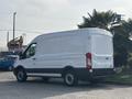 A 2016 Ford Transit 150 van in white with black accents parked at an angle showing its side and rear features