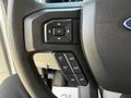 Close-up of the steering wheel controls of a 2023 Ford E-450 showing buttons for adjusting settings and cruise control