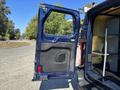 A 2016 Ford Transit 150 with the driver's side door open displaying the interior structure and storage compartments