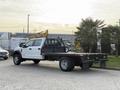 A 2020 Ford F-550 flatbed truck with a white cab and black bed parked on a concrete surface