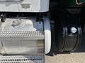 A close-up view of a 2015 Peterbilt 337 featuring a silver aluminum fuel tank with a circular cap and a black fuel tank with a round cap