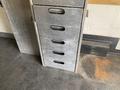 A metal storage cabinet with five drawers, each featuring a handle for opening and a metallic finish, showing signs of wear and use