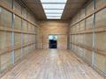 Interior view of a 2024 Ford E-450 cargo van showing wooden flooring and walls with metal framing and a cutout for the driver's cab