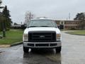 A white 2008 Ford F-250 SD pickup truck with a large front grille and headlights facing directly forward