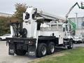 A 2013 Freightliner 114SD truck equipped with a white utility boom lift and a flatbed trailer attached to its rear