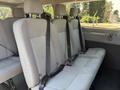 Interior view of a 2016 Ford Transit 150 showing three rows of gray fabric seats with seat belts attached