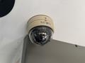 A security camera mounted on a ceiling with a dome shape and the label SEON visible on its surface