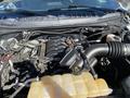 The engine compartment of a 2018 Ford F-150 featuring a black air intake and a yellow coolant reservoir with various hoses and components visible