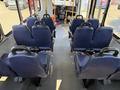 Interior of a 2020 Chevrolet Express with several blue fabric seats arranged in rows facing forward and a driver compartment visible at the front