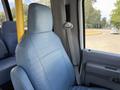 Interior view of a 2013 Ford Econoline with a blue upholstered driver's seat and a seatbelt visible