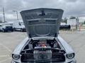 A 1968 Ford Mustang two door convertible with the hood raised displaying a detailed engine compartment