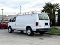 A white 2008 Ford Econoline van with a roof rack parked from the rear angle showcasing its large cargo space and simple design
