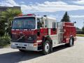 A red and silver 1994 Volvo FE 42 fire truck with flashing lights on the roof and a prominent Volvo logo on the front grille