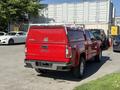 A red 2018 GMC Canyon pickup truck with a cap on the bed parked in a lot visible from the rear angle