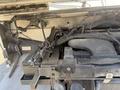 A 2012 Ford Econoline engine compartment showing the engine components and wiring with visible rust and a battery on the left side
