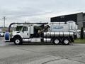 A 2013 International Workstar 7500 truck equipped with a vacuum system featuring a large cylindrical tank and a hose attached on the side.