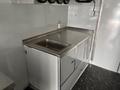 A stainless steel kitchen counter with an integrated sink and storage compartments designed for food preparation in a mobile food service vehicle