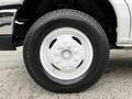 A close-up of a white wheel with a six-bolt pattern and treaded black tire on a 2019 Ford Econoline