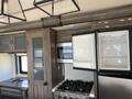 Interior view of a 2021 Grand Design Recreational ST3478MBS featuring a kitchen area with a stove refrigerator and cabinets